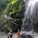 Two students sitting on rocks by waterfall in Costa Rica